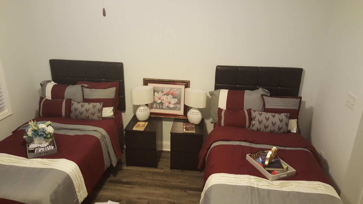 A cozy bedroom featuring twin beds with matching linens, a shared nightstand adorned with lamps, and a decorative frame.