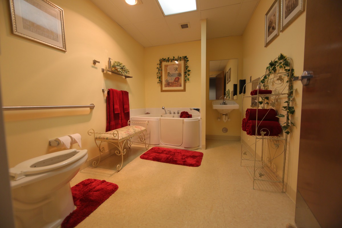 A well-decorated bathroom with red accents, featuring a bathtub, sink, and neatly arranged towels.