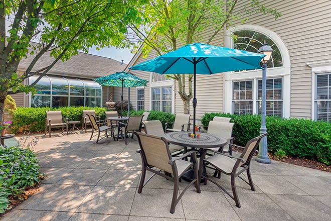 A sunny patio area with tables, chairs, and umbrellas.