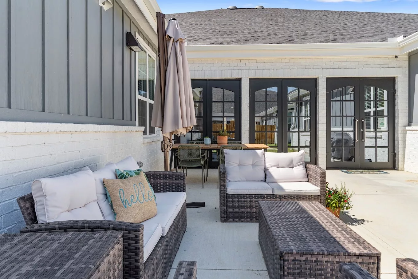 A cozy patio with wicker furniture and cushions, featuring a modern outdoor design.