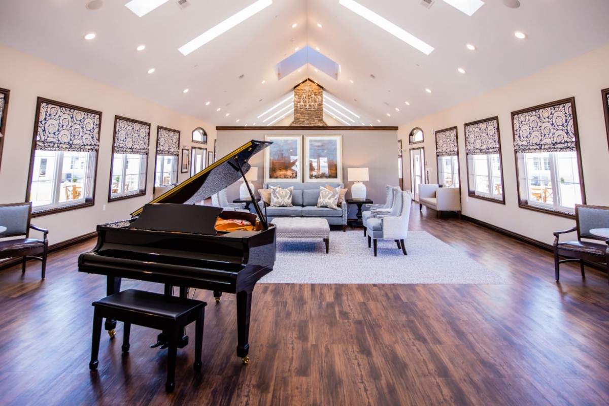 A luxurious and spacious living room featuring a grand piano, hardwood floors, and ample natural light.