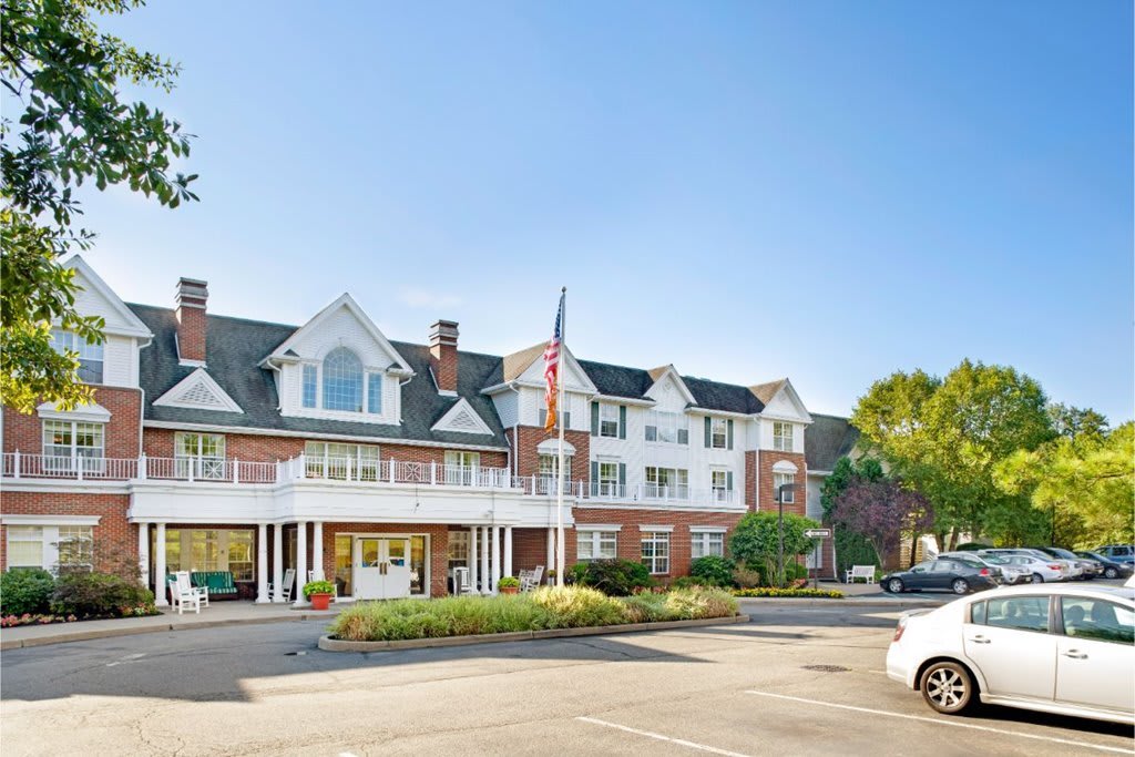 A large residential building with a driveway and well-maintained landscaping on a sunny day.