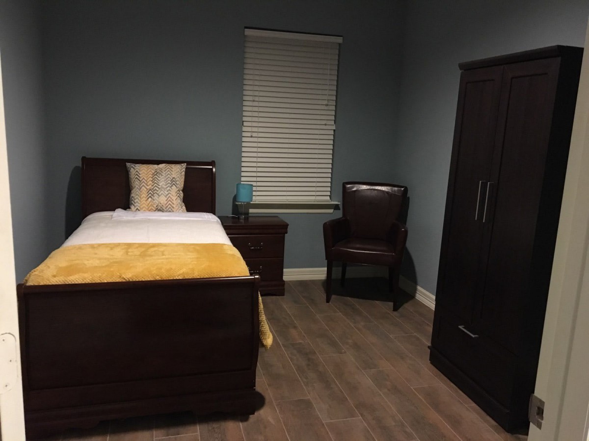 A cozy bedroom with a single bed, wardrobe, and nightstand.