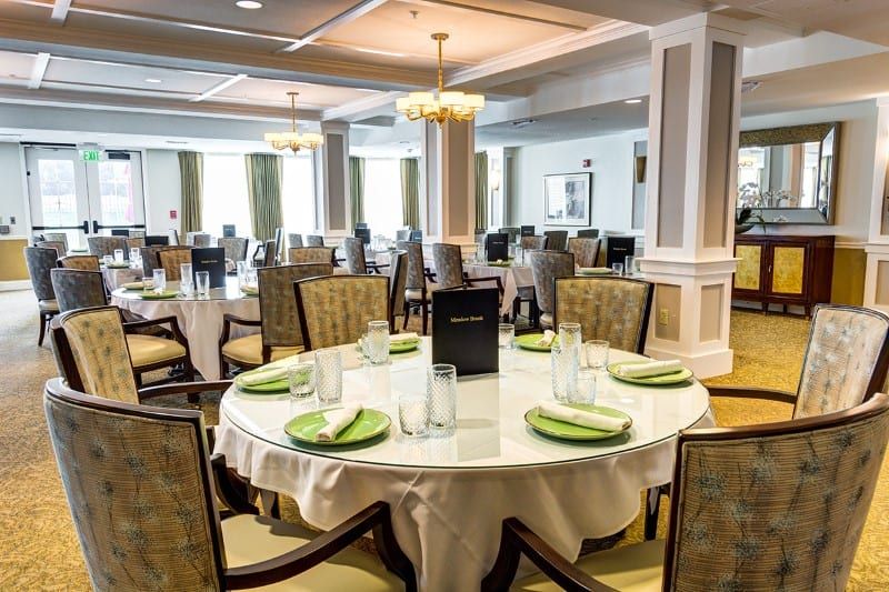 An elegantly set dining room with round tables, chairs, and ambient lighting.