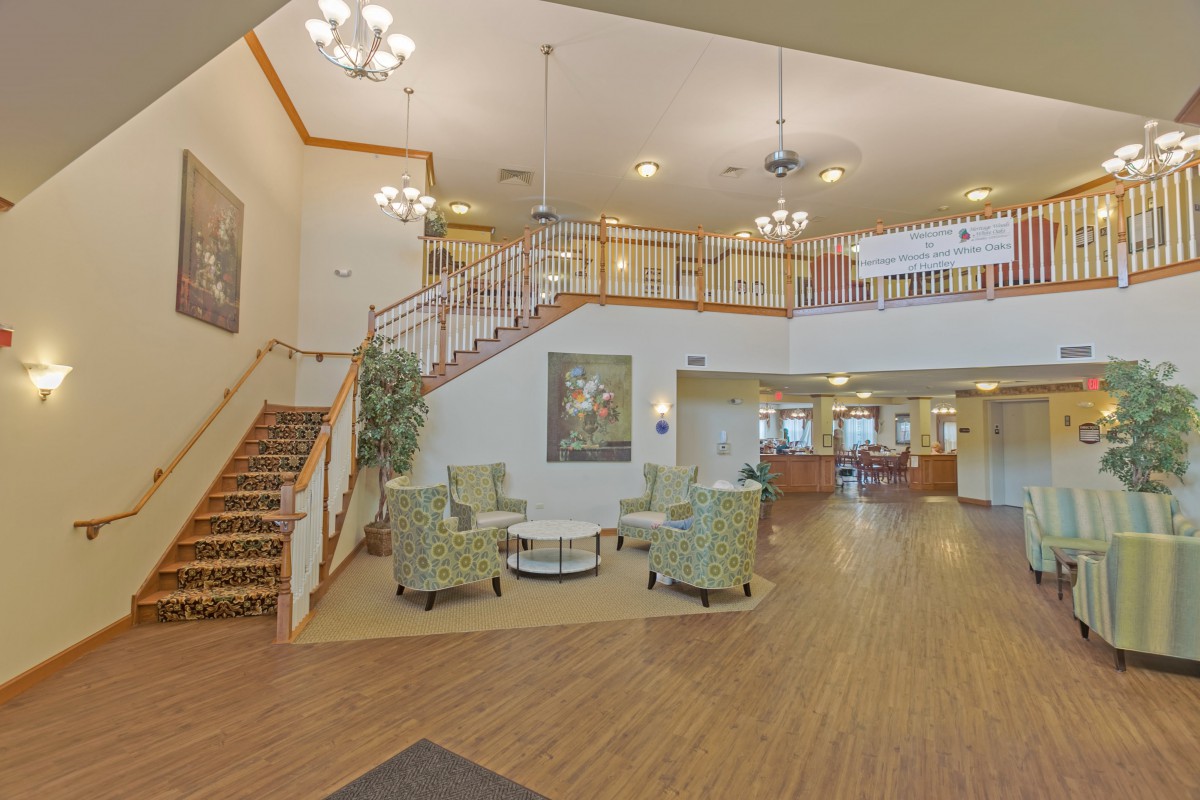 A well-lit lobby with a seating area, staircase, and reception desk.
