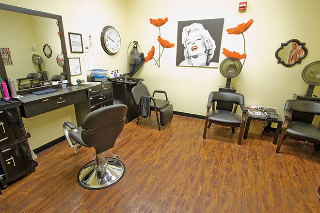 Interior of a hair salon with chairs, a mirror, and wall art.