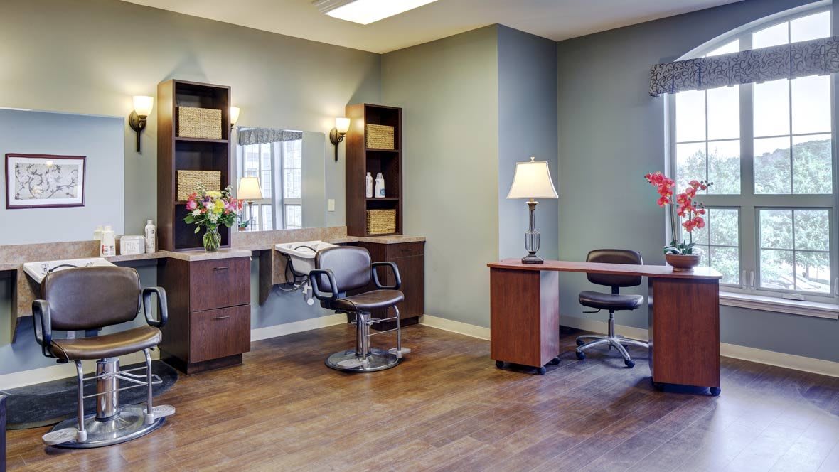 A well-lit salon interior with workstations featuring chairs, mirrors, and elegant decor.