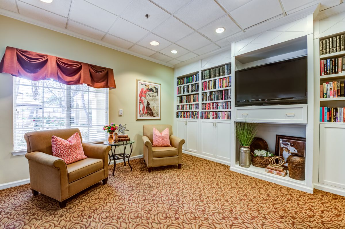 A cozy living room with armchairs, bookshelves, and a television.