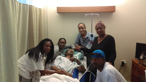 A family gathers around a patient in a hospital room, providing love and support during a difficult time.