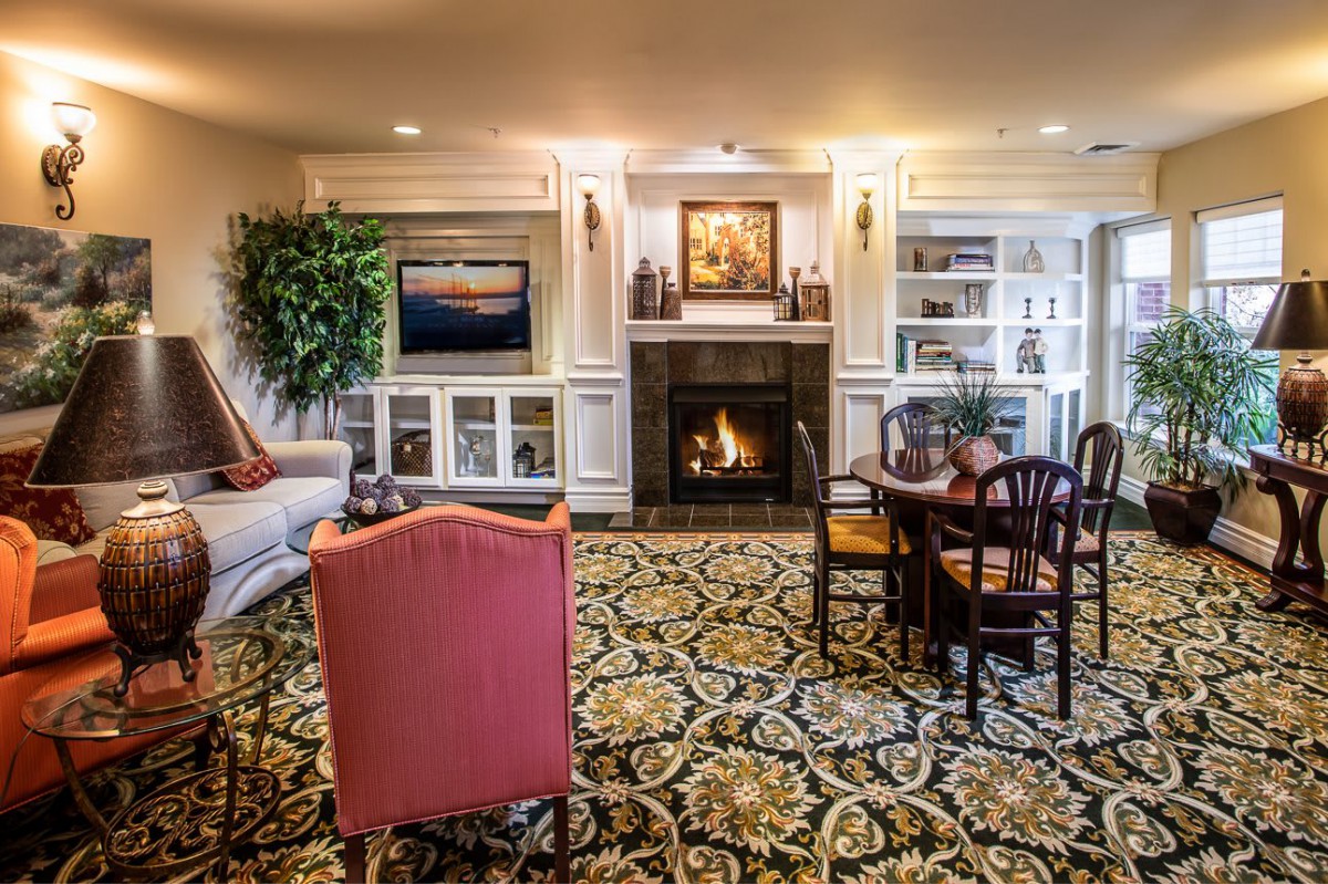 A cozy living room with a fireplace, elegant furniture, and intricate carpet design.