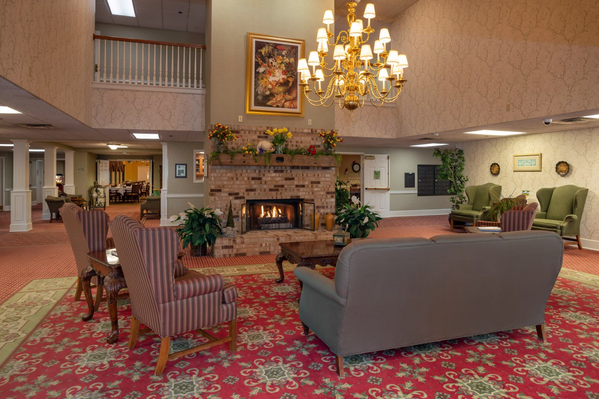 A cozy lobby with a warm fireplace, elegant chandelier, and comfortable seating area.