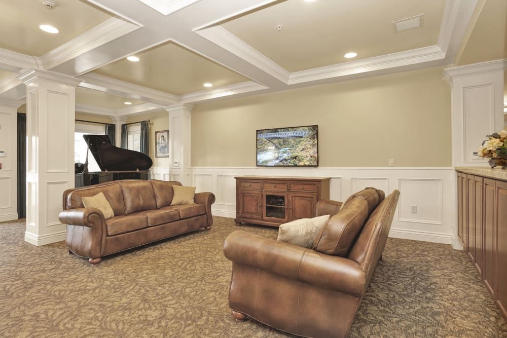 A cozy living room featuring leather sofas, a grand piano, and elegant interior design.