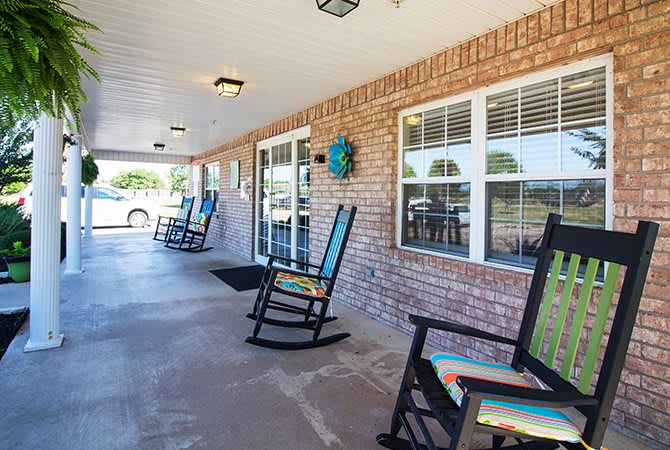 A peaceful porch with rocking chairs along a brick wall.