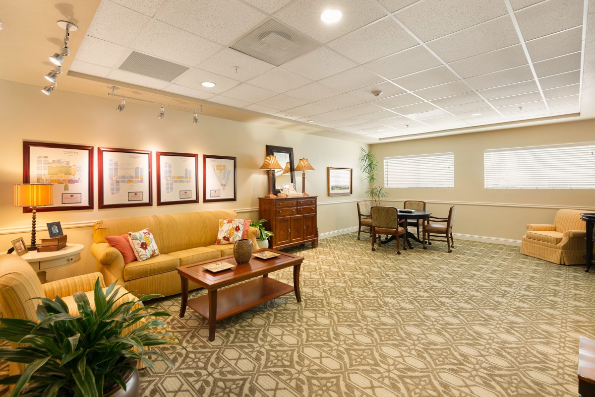 A cozy living room space featuring a comfortable sofa, artwork on the walls, and a small dining area.