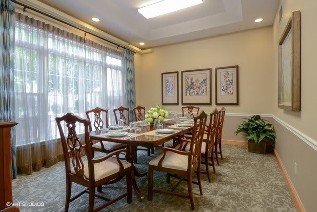 A well-decorated dining room with a large table and chairs, artwork on the walls, and a window allowing natural light.