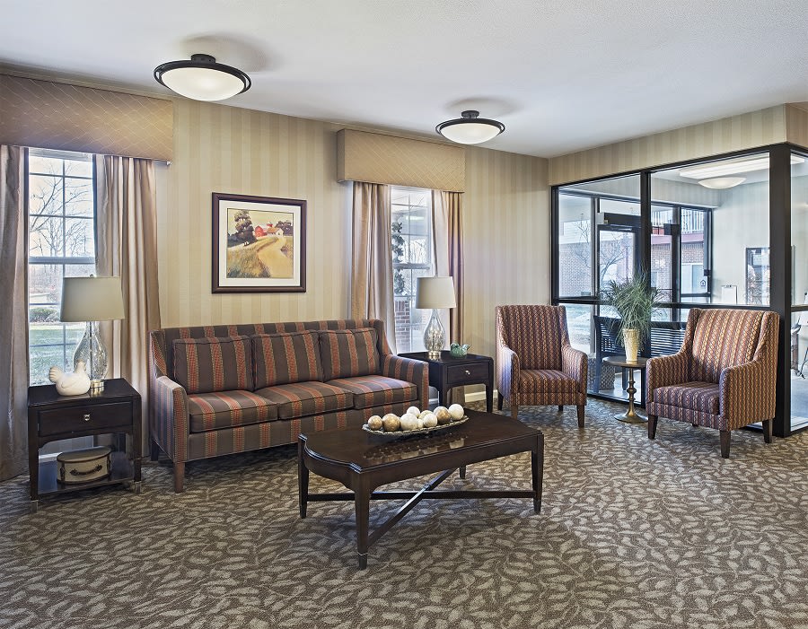 A cozy living room with a sofa, armchairs, and a coffee table on a patterned carpet.
