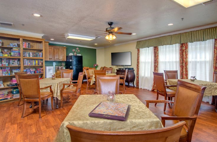A cozy dining area with multiple tables and chairs, wooden furniture, a ceiling fan, and a television.