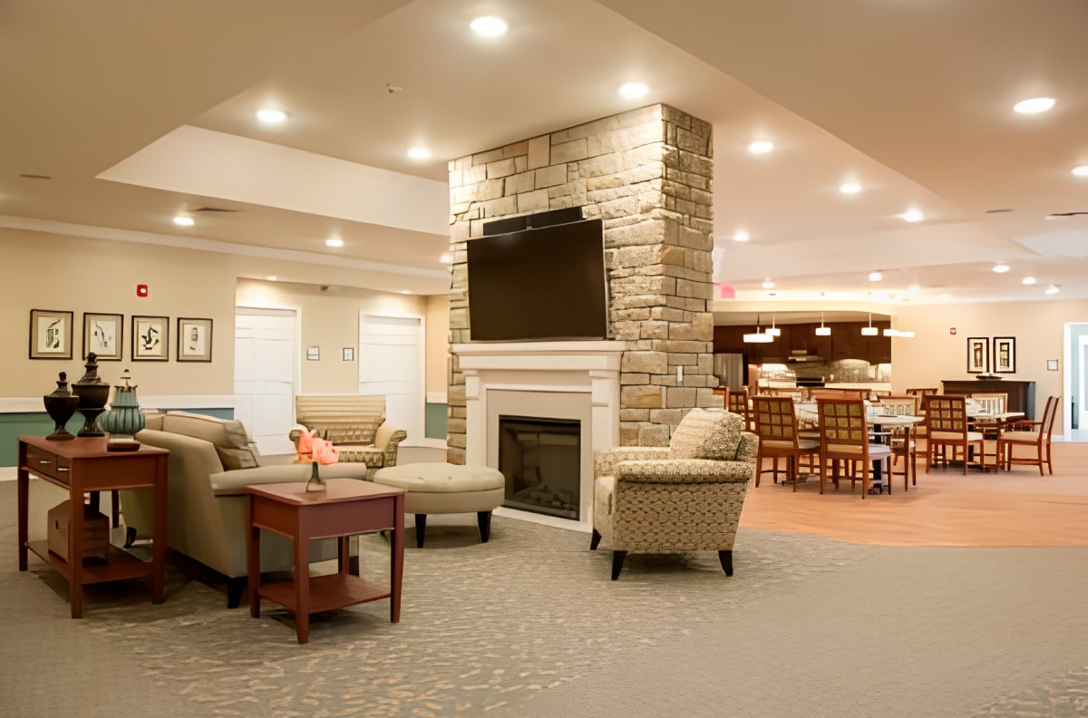 A modern living room with a cozy seating area, featuring a stone fireplace and a mounted television.