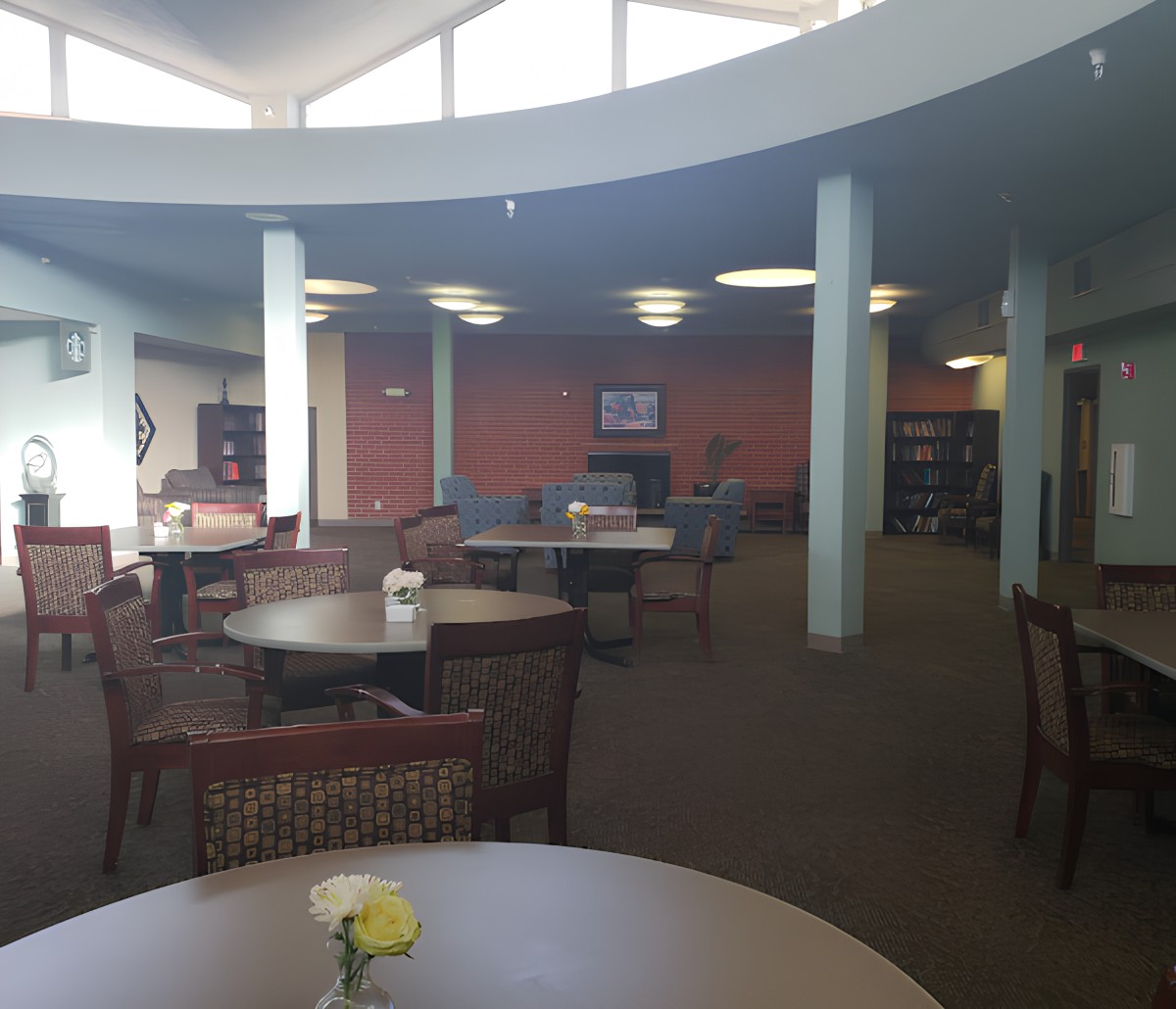 A quiet library study area with tables, chairs, and bookshelves.