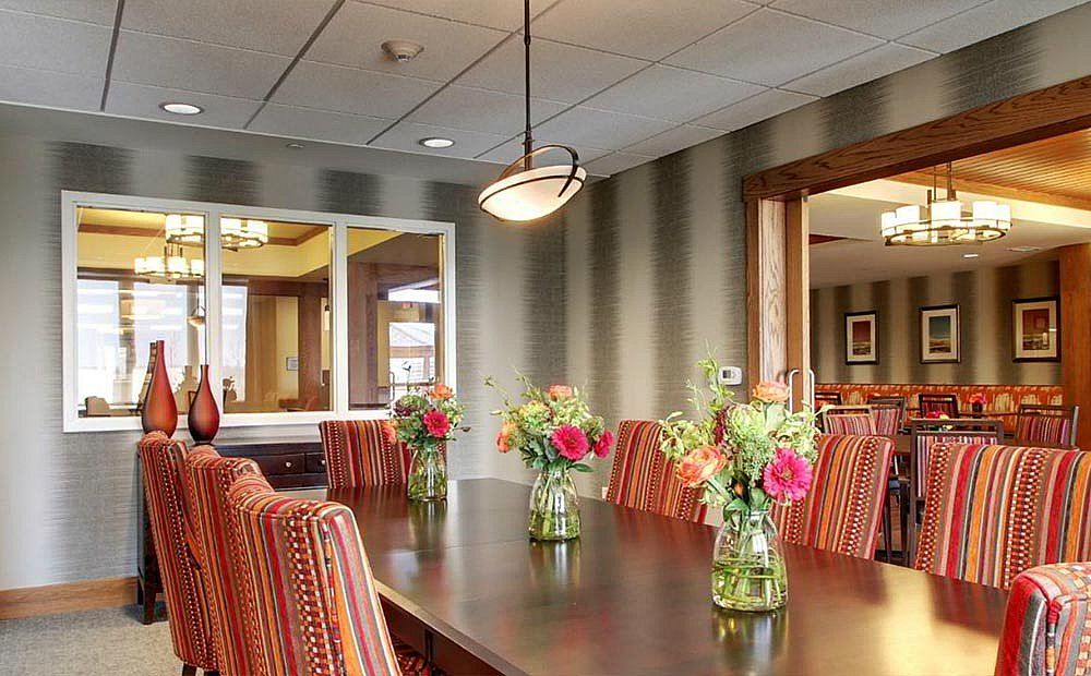 A dining room with a long table, adorned with vases of flowers and surrounded by patterned chairs.