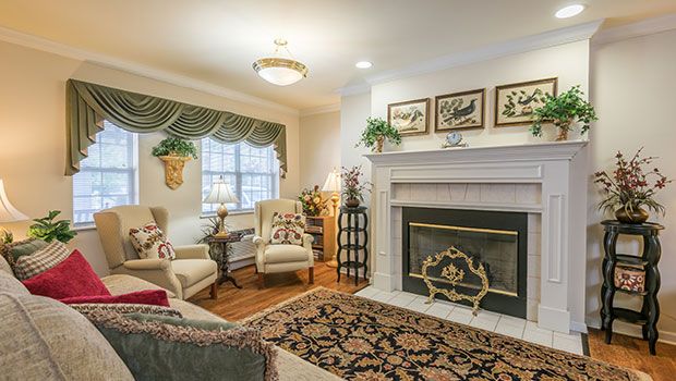 A cozy living room with traditional decor, featuring a fireplace and comfortable armchairs.