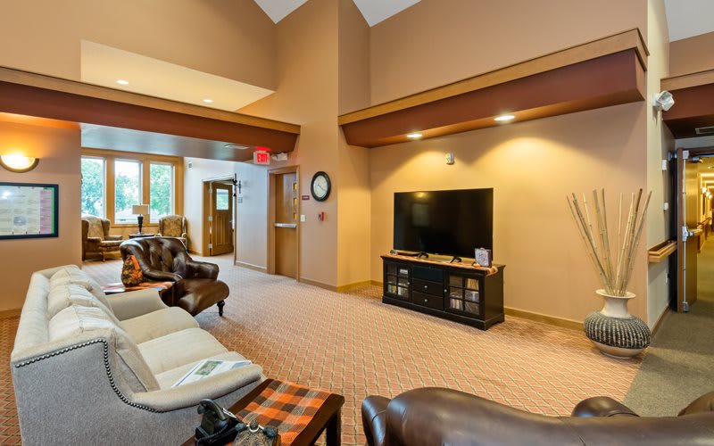 A spacious living room featuring comfortable seating, a large TV, and warm interior accents.