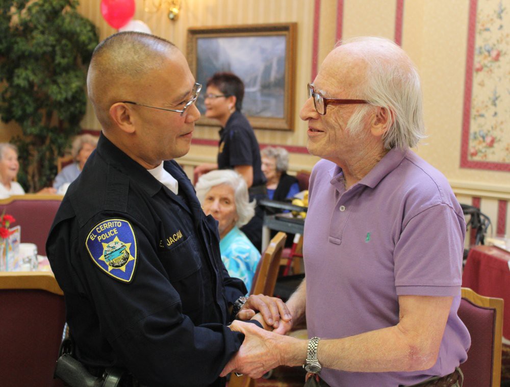 A police officer engages in a friendly conversation with an elderly man at a community event.