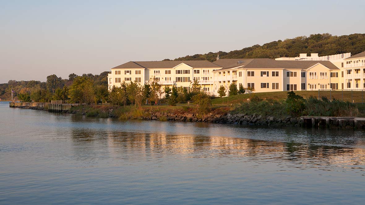A large building reflecting in the calm waters at sunset.