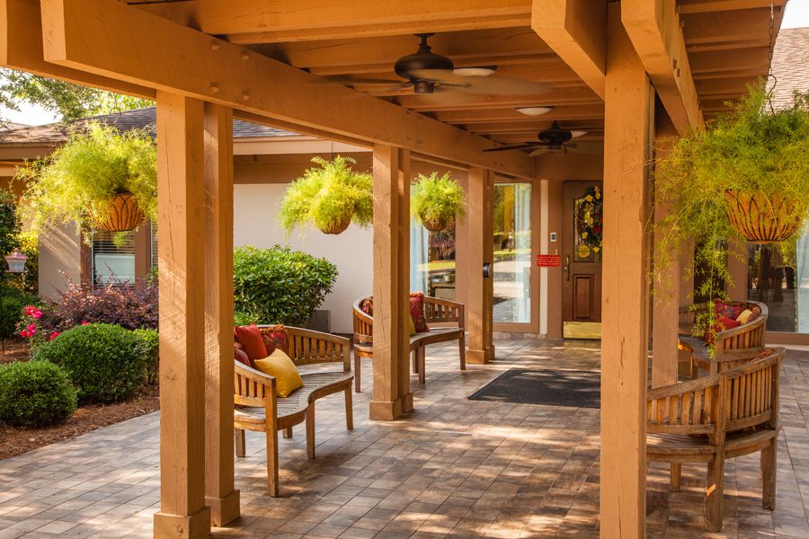 A cozy outdoor patio with wooden beams, comfortable seating, and hanging plants.