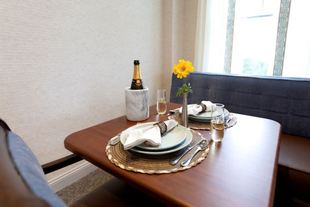A beautifully set dining table with champagne, elegant plates, and a flower centerpiece.
