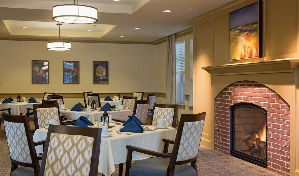 An elegantly designed restaurant dining room with neatly set tables and a cozy fireplace.