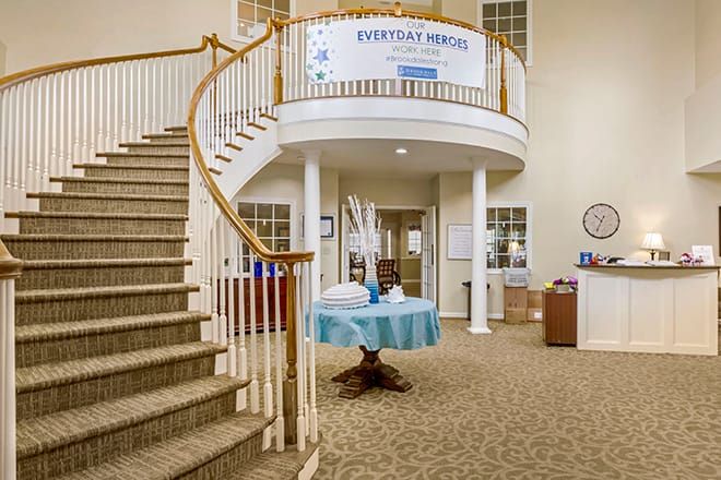 A welcoming lobby featuring a grand staircase and a central table, with a banner displayed above.