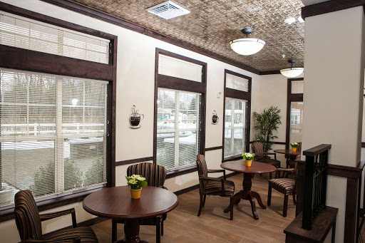 A cozy and inviting waiting area featuring wooden tables and chairs, adorned with small potted plants.