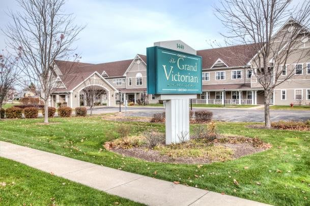 A large building with a green sign out front on a grassy area