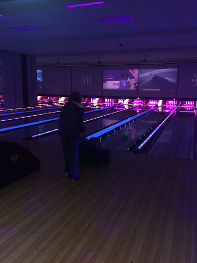 A person enjoying a game in a vibrant, neon-lit bowling alley.