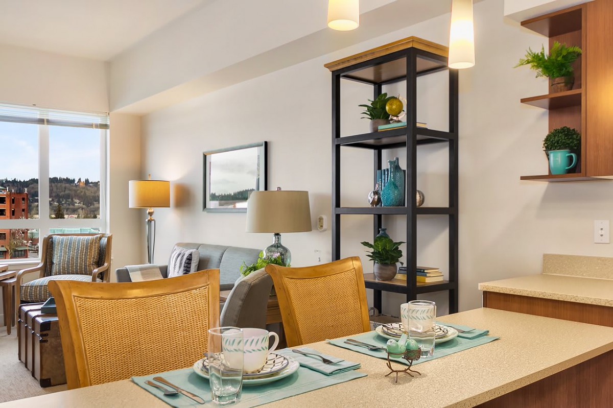 A modern dining area with a neatly set table and stylish shelving in the background.