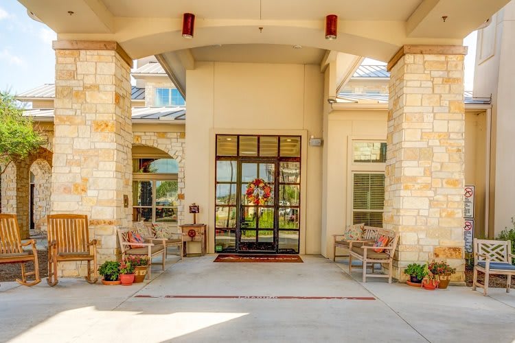 A welcoming building entrance with chairs and potted plants.