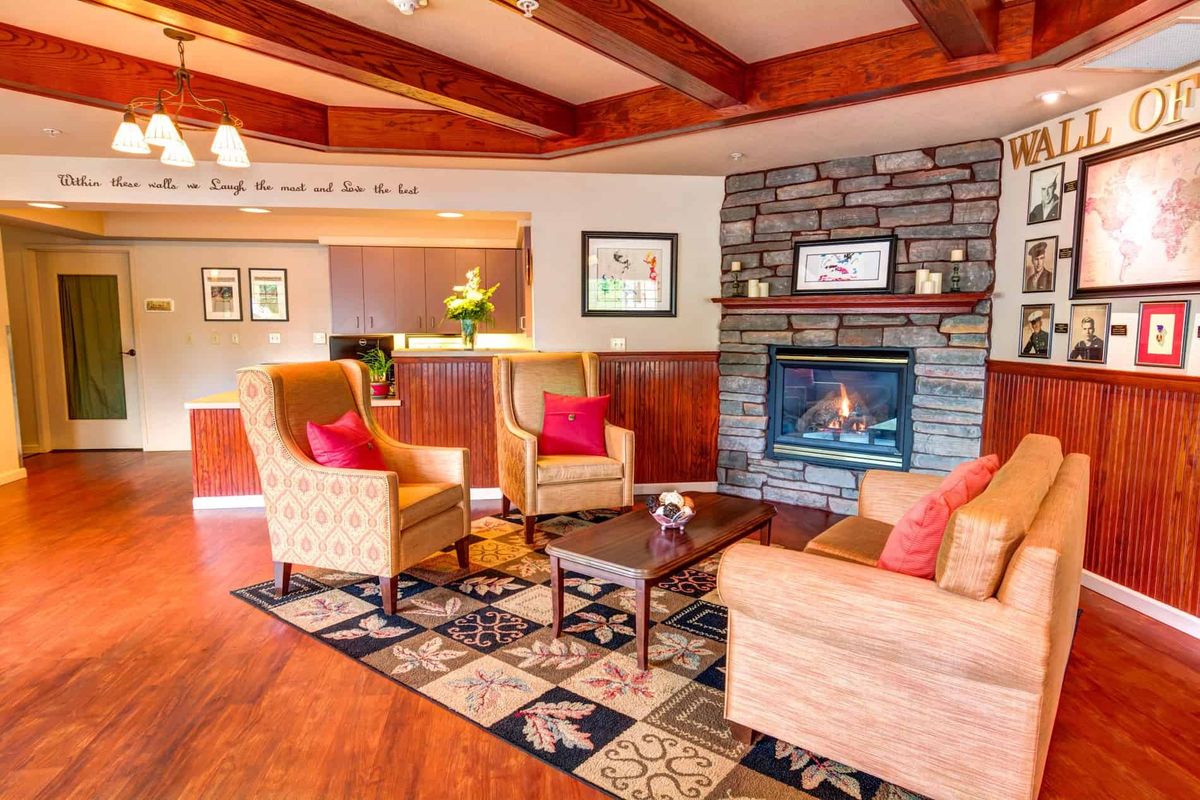 A cozy living room with modern furniture, featuring a fireplace and wooden beams.