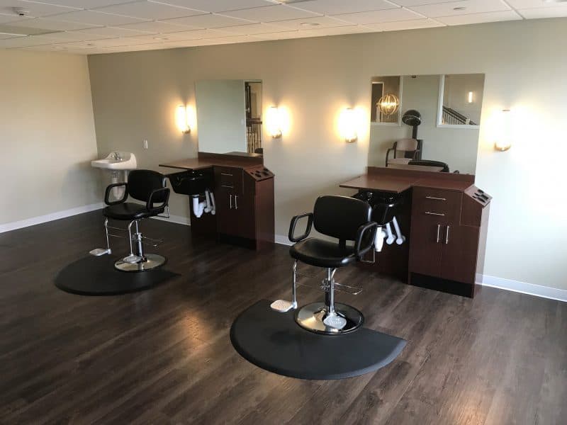 An empty barber shop with chairs and mirrors lined up neatly.