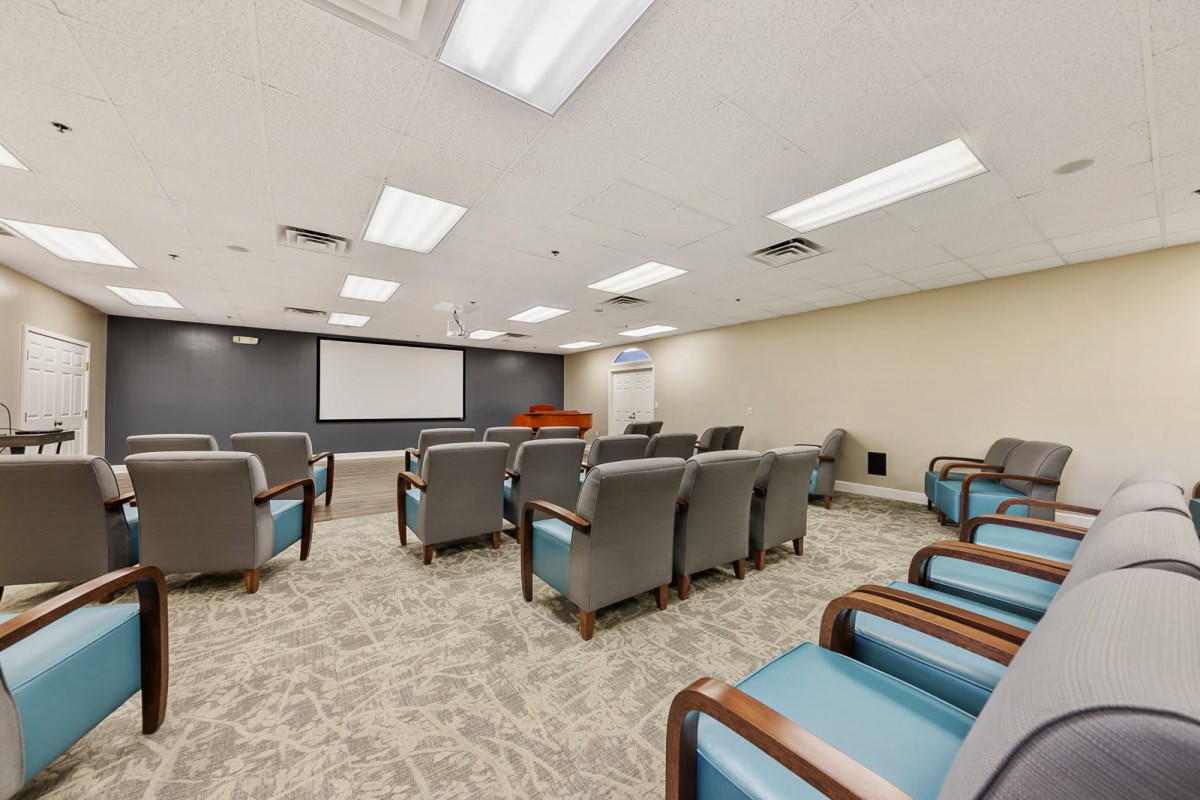 A spacious conference room equipped with comfortable seating and a large projector screen.