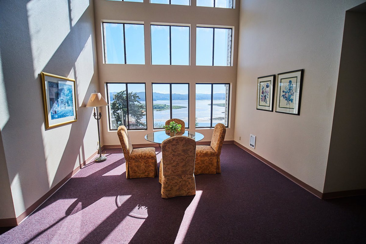 A spacious room with large windows offering a scenic view, featuring a small dining setup.