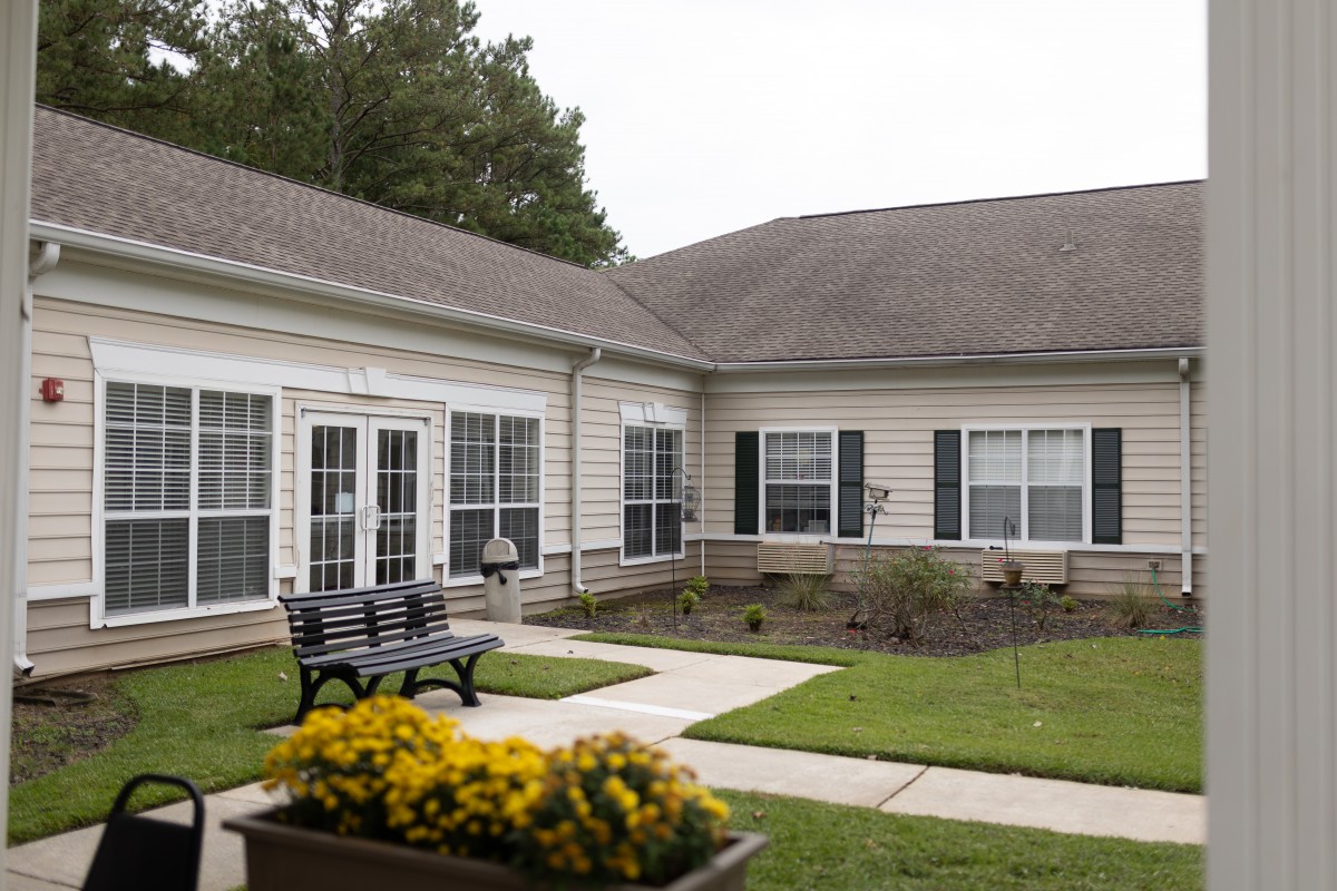 A courtyard area with a bench and flowers outside a residential building.