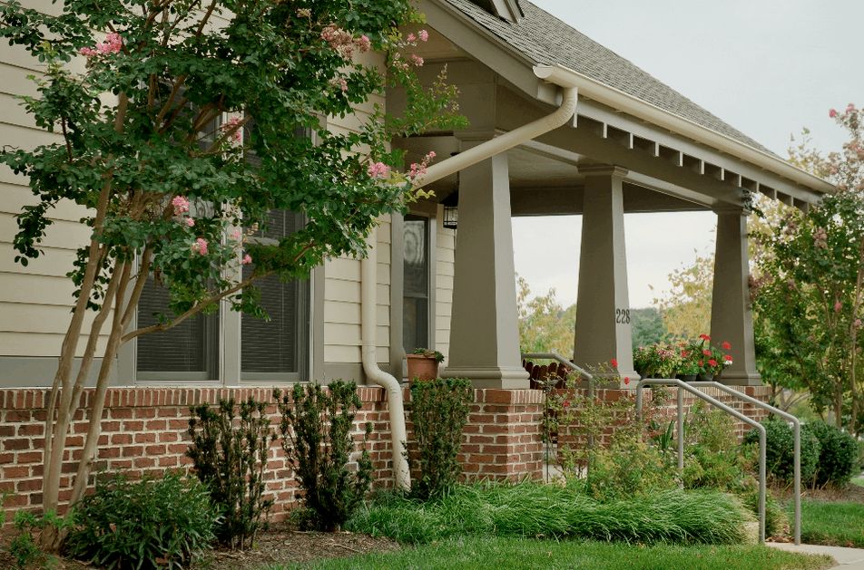 A charming house with a porch surrounded by lush greenery.