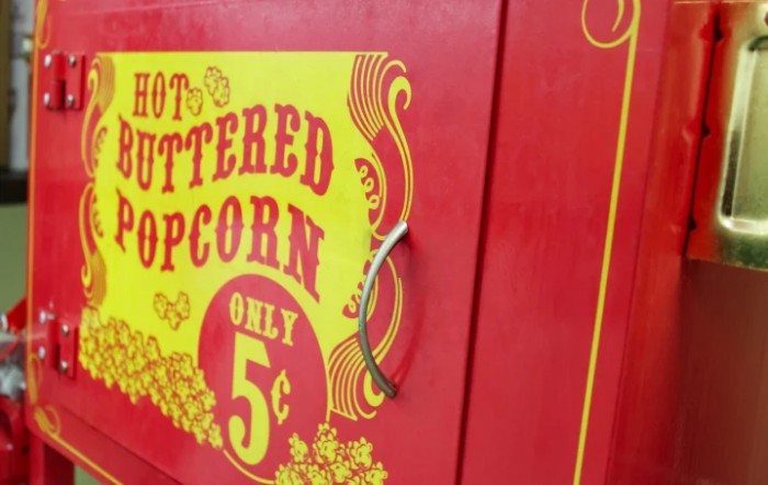 A vintage-style sign advertising hot buttered popcorn for only 5 cents.