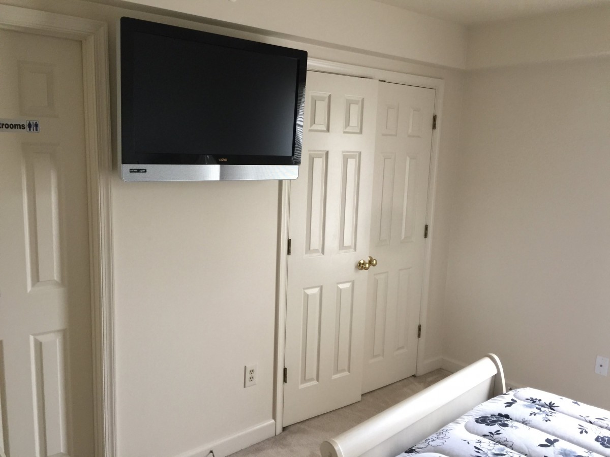 A bedroom featuring a wall-mounted television above a closet door.
