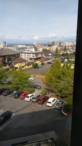 A view of a bustling city with a parking lot in the foreground and various buildings in the background.