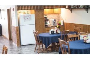 A cozy kitchen-dining area with wooden furniture and blue tablecloths on the tables.