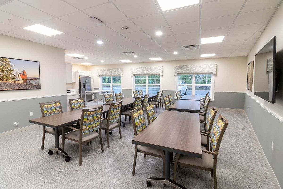 A spacious dining room with neatly arranged tables and chairs, featuring large windows for natural light.