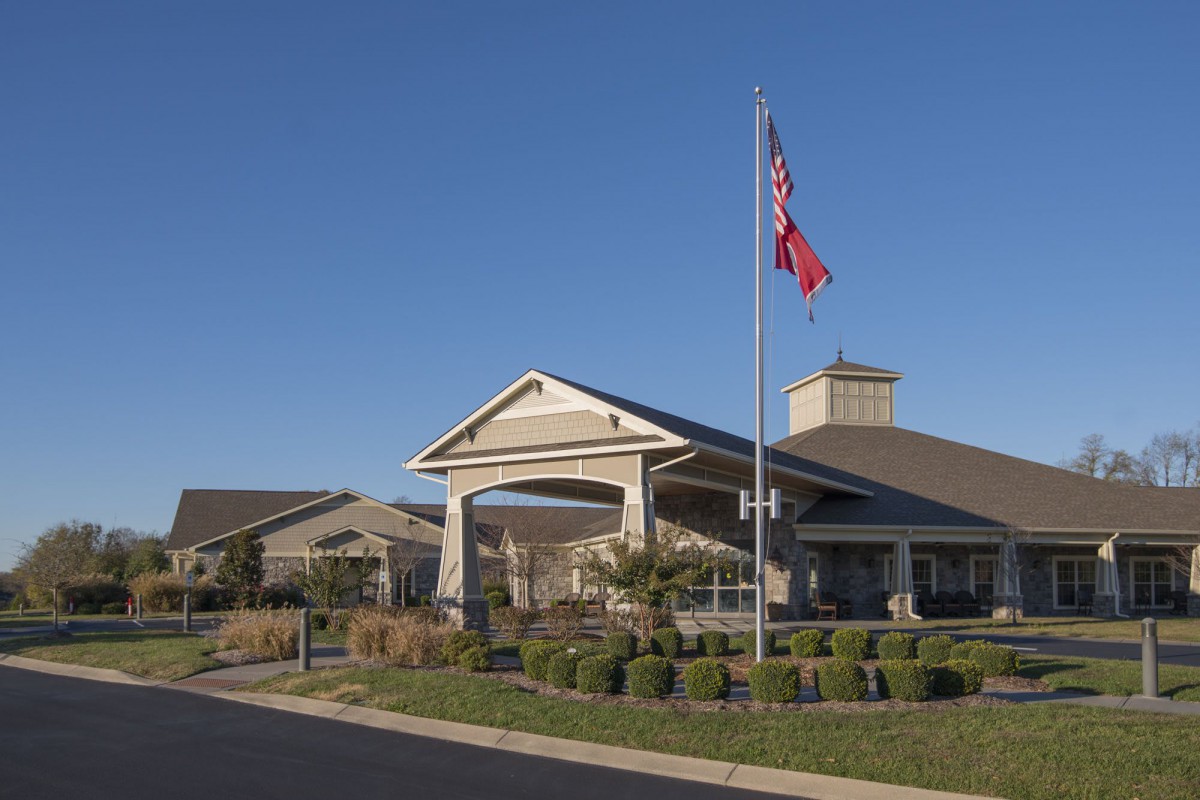 A building with flags flying in front, surrounded by neatly trimmed landscaping on a clear day.