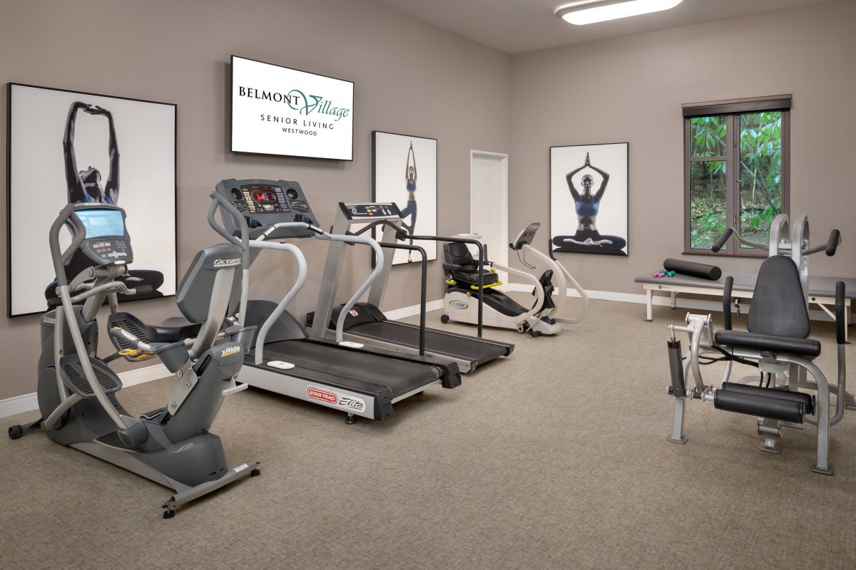 A well-equipped gym with treadmills, a stationary bike, weights, and yoga-themed decor.